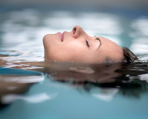 Woman at the spa relaxing at the swimming pool floating with eyes closed
